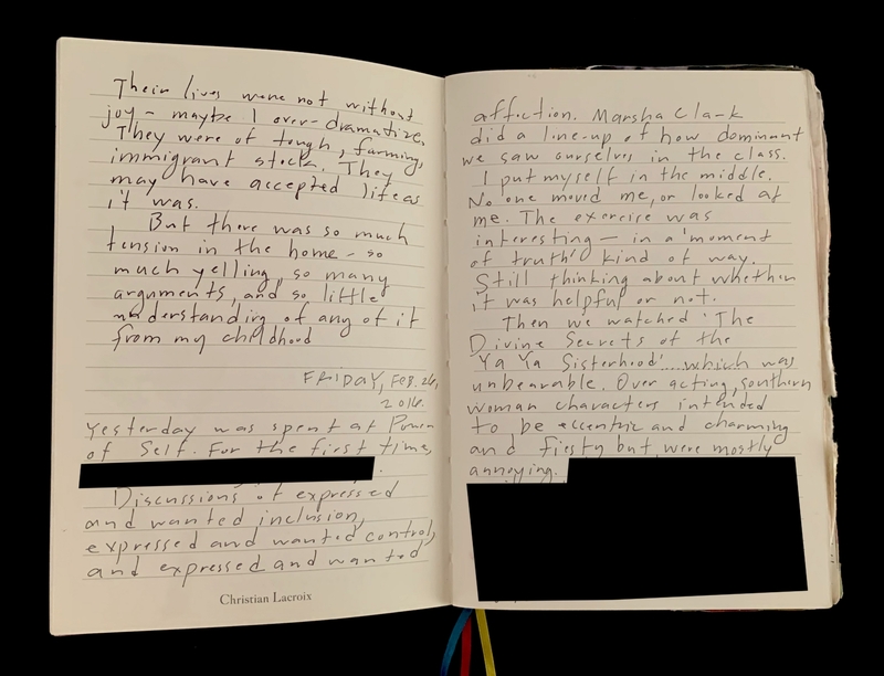An open journal with handwritten text and some sections redacted in black.