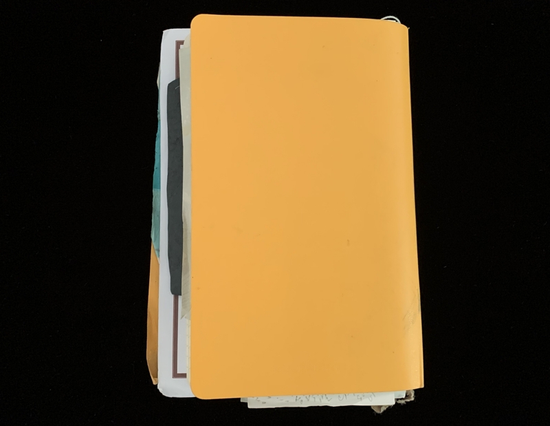 An orange folder with papers sticking out against a black background.