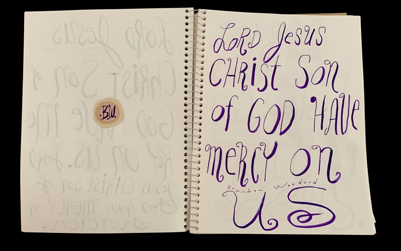 A handwritten prayer page featuring a bold inscription and a small circular sticker.