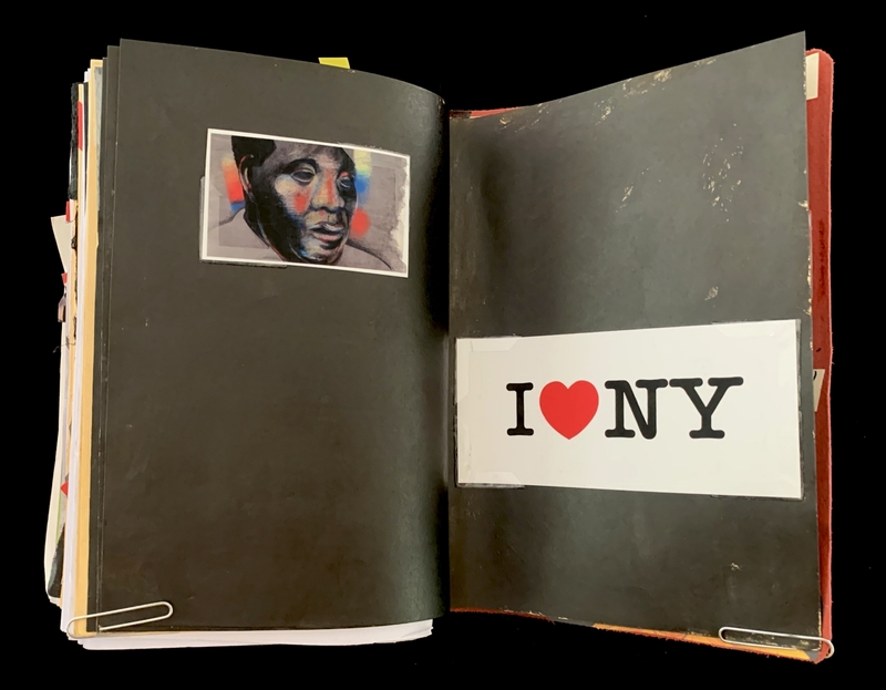 A black scrapbook page featuring a painted portrait and a "I ❤️ NY" sticker.