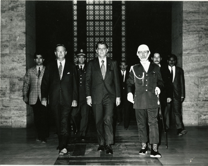 Clifford Hardin walks out of building doorway with two unidentified men, on is a guard, in Turkey.