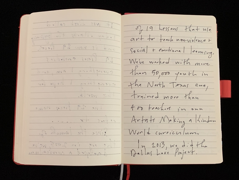 An open notebook with handwritten text on a red-spined lined page against a black background.