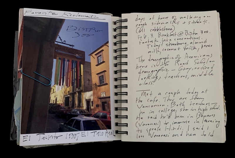 A travel journal page featuring a photograph of a street scene and handwritten notes about a restaurant and a meeting.
