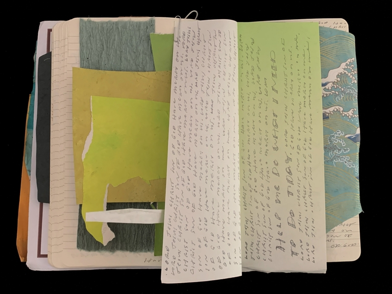 An open notebook filled with layered colorful papers and handwritten notes.