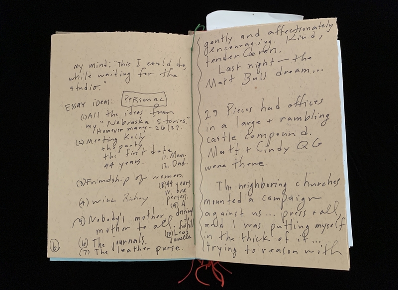 Open notebook with handwritten reflections and essay ideas on light brown paper.