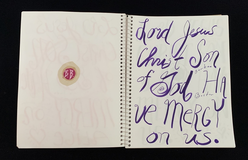 A handwritten page with a prayer and a sticker.