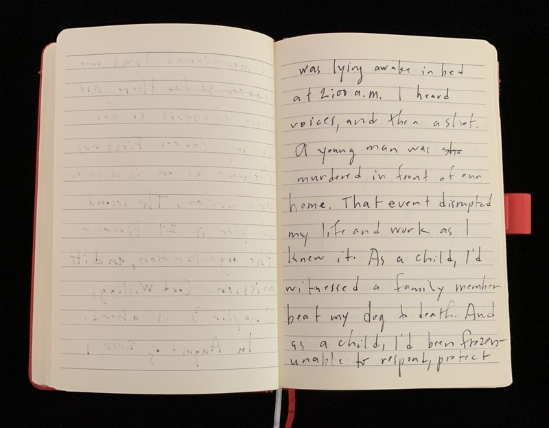 An open notebook with handwritten text on one page against a dark background.