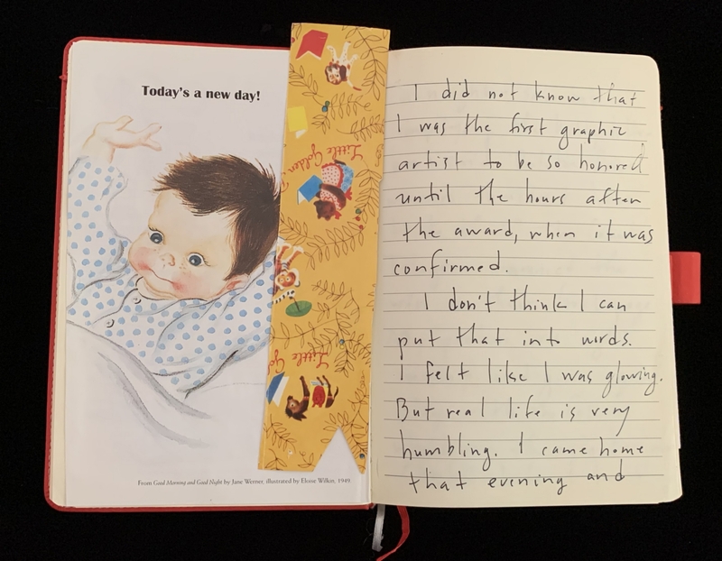 An open book showing a baby illustration on the left and handwritten text on the right.