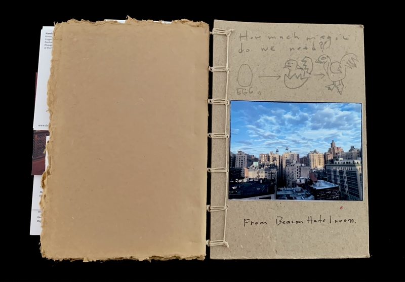 An open book showing a hand-drawn diagram and a cityscape photo on one page.