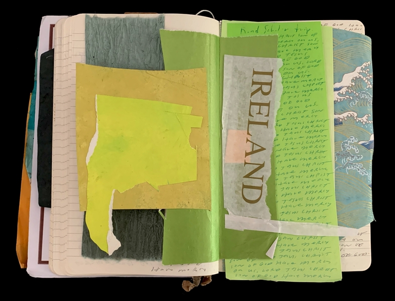 Open notebook with layered torn paper and notes, featuring "IRELAND" on translucent paper.