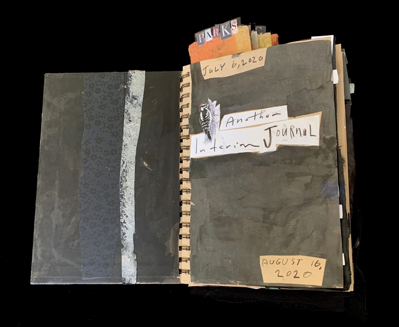 A handmade journal with a dark cover, featuring handwritten text and a small illustration of a bird.