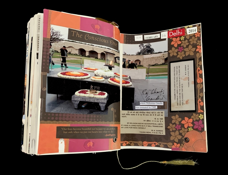 A scrapbook page commemorating a visit to Raj Ghat, the memorial site where Mahatma Gandhi was cremated in 1948, featuring floral arrangements and quotes.