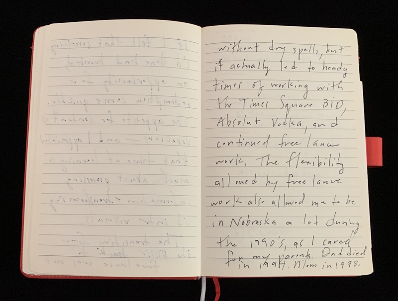Open notebook with handwritten text on the right page in black ink on a dark surface.