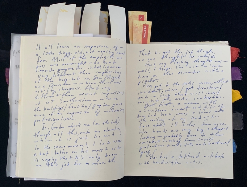 Open journal with handwritten blue text and colored ribbon markers.