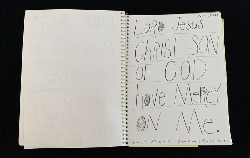 A handwritten page with a prayer and some faint, repeated text on the left side.