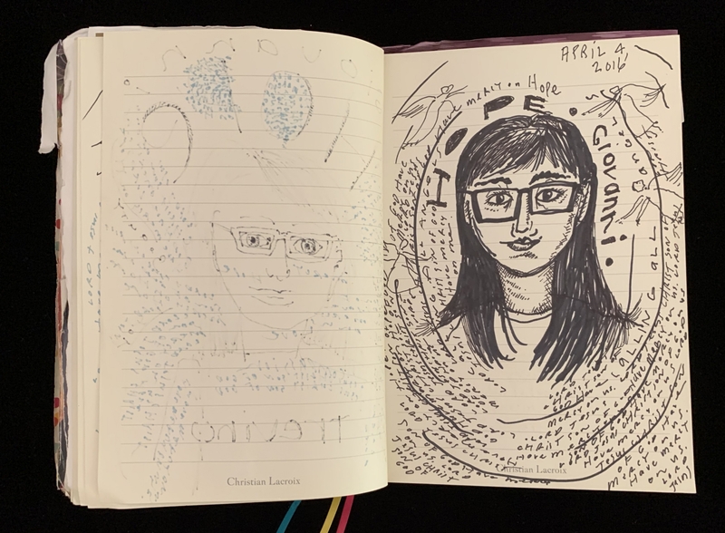 An open journal showing drawings of a face with glasses and handwritten text.