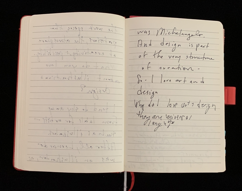 Open notebook with handwritten text, red cover visible.
