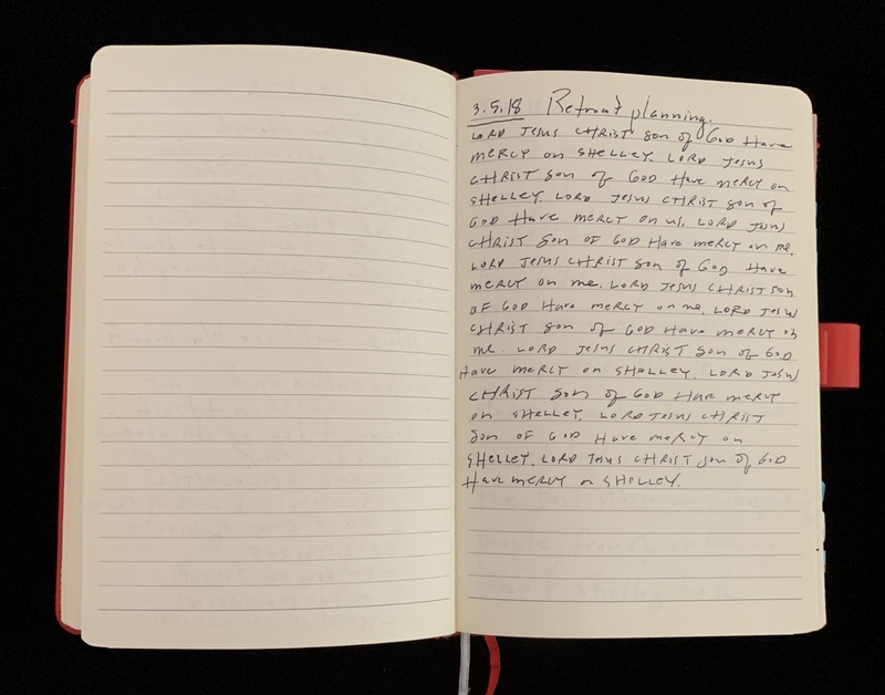Open notebook with handwriting on the right page and a red cover.