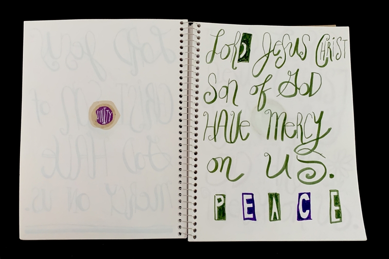 A handwritten page featuring a prayer and decorative elements, with a circular sticker and faint script in the background.