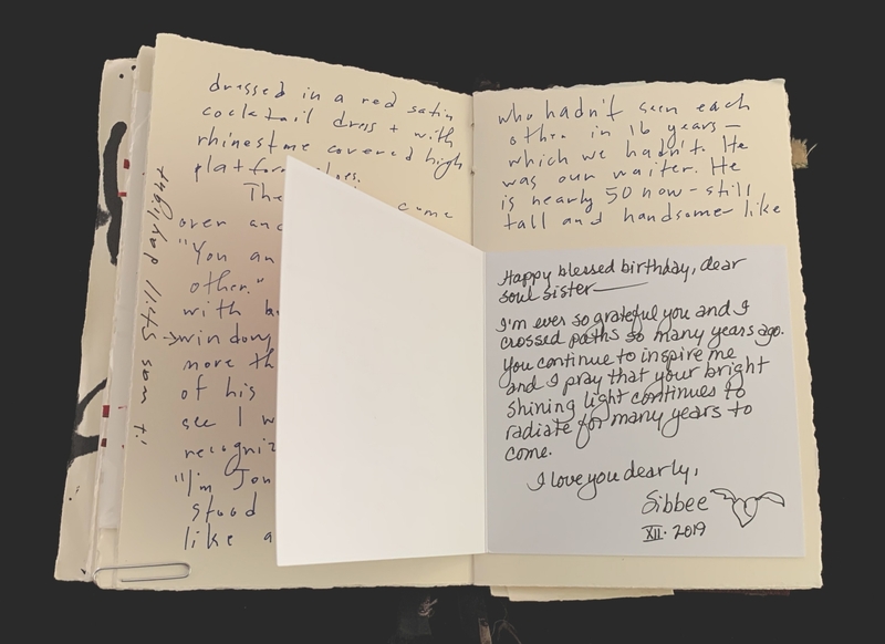Open book with handwritten text and an overlaid greeting card with a personal message.