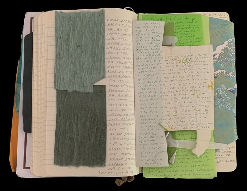 An open notebook with handwritten notes and several sheets of colored paper inserted.
