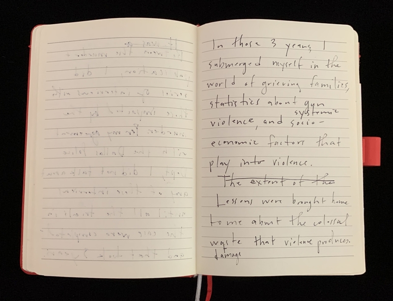 An open notebook with red binding filled with handwritten text on both visible pages.