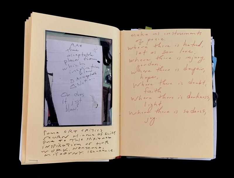 A handwritten page with various notes and a reflective surface showing a person's reflection.