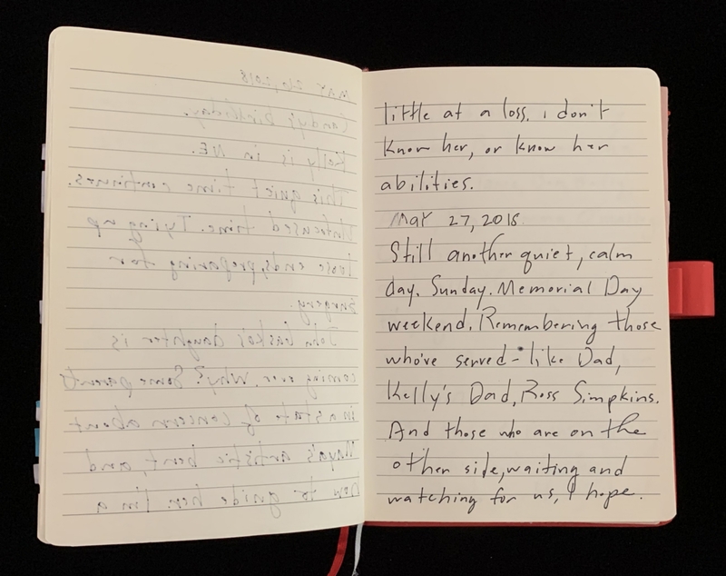 Open notebook with handwritten text, featuring two pages, one with upside-down writing.
