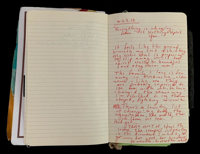 Open notebook with handwritten red ink on the right page and a blank left page.