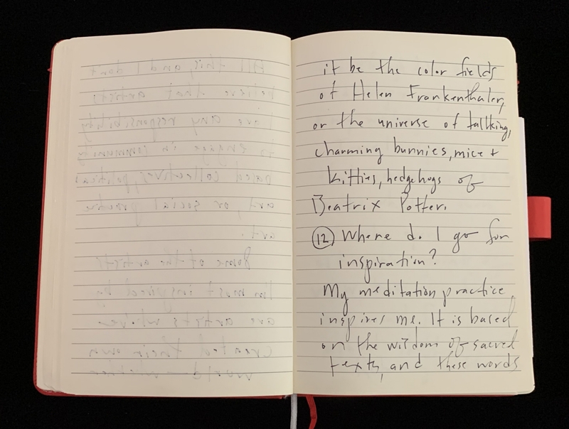 Open notebook with handwritten text on a black surface; the right page has legible cursive writing and a circled number "12".