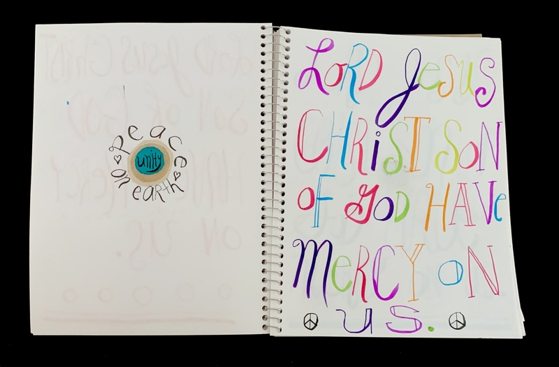 A spiral-bound notebook page featuring colorful calligraphy and a small circular design.