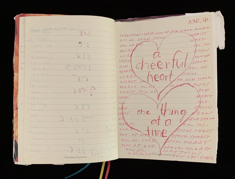 Open journal with overlapping heart illustrations containing text "a cheerful heart" and "one thing at a time" on the right page.