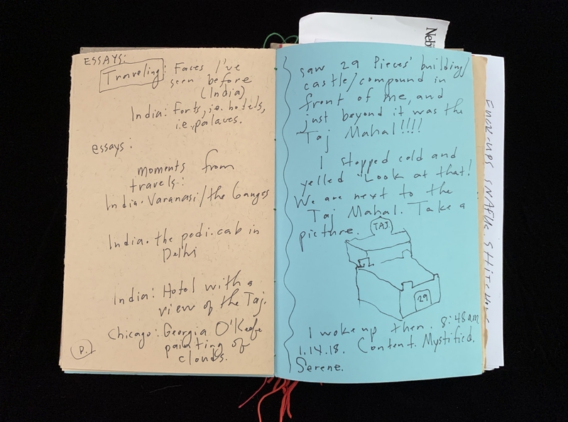 Open notebook with handwritten travel notes on beige and blue pages.