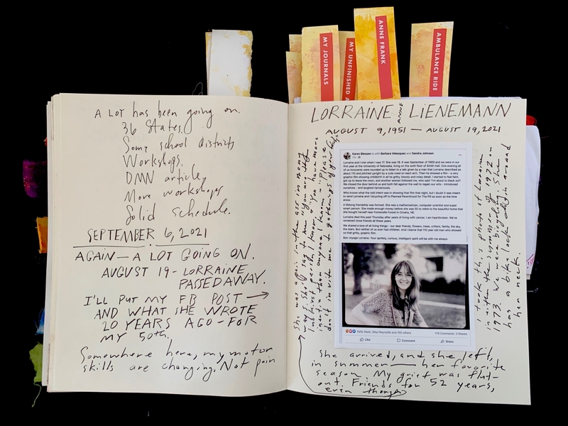 An open journal with handwritten notes and a pasted article memorializing Lorraine Lienemann, with colorful index tabs sticking out.