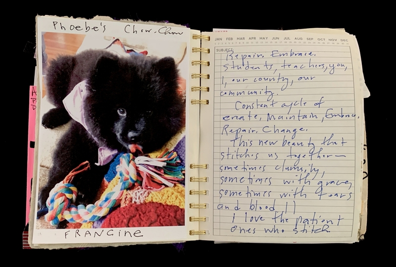 A handwritten note in a spiral-bound notebook accompanied by a photograph of a black puppy named Phoebe's Chow Chow.