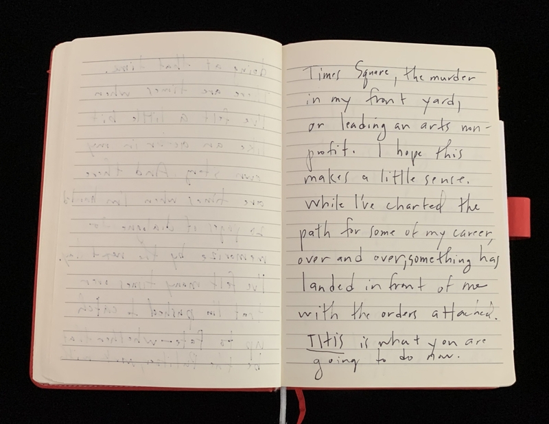 Open notebook with handwritten text on the right page, set against a black background.