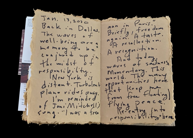 Open notebook with handwritten text on aged, rough-edged pages.
