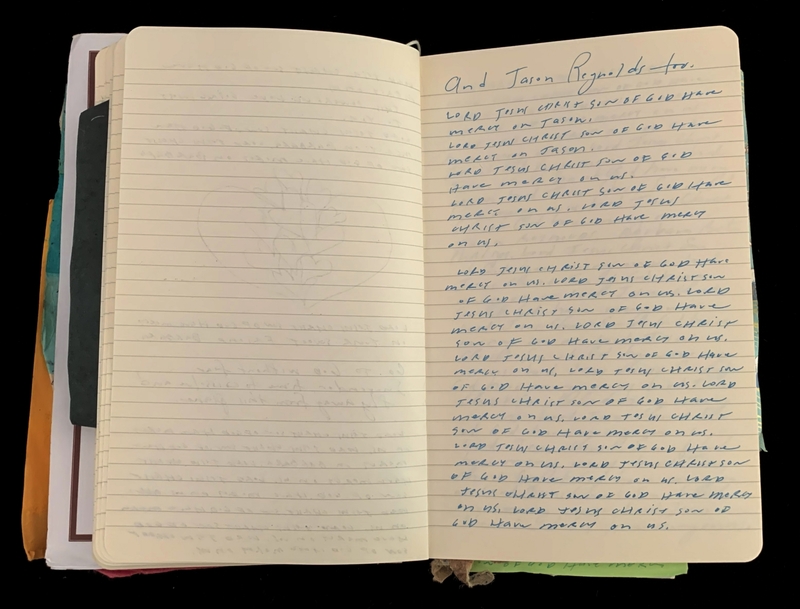Open notebook with pages of handwritten blue ink text and colored papers sticking out.