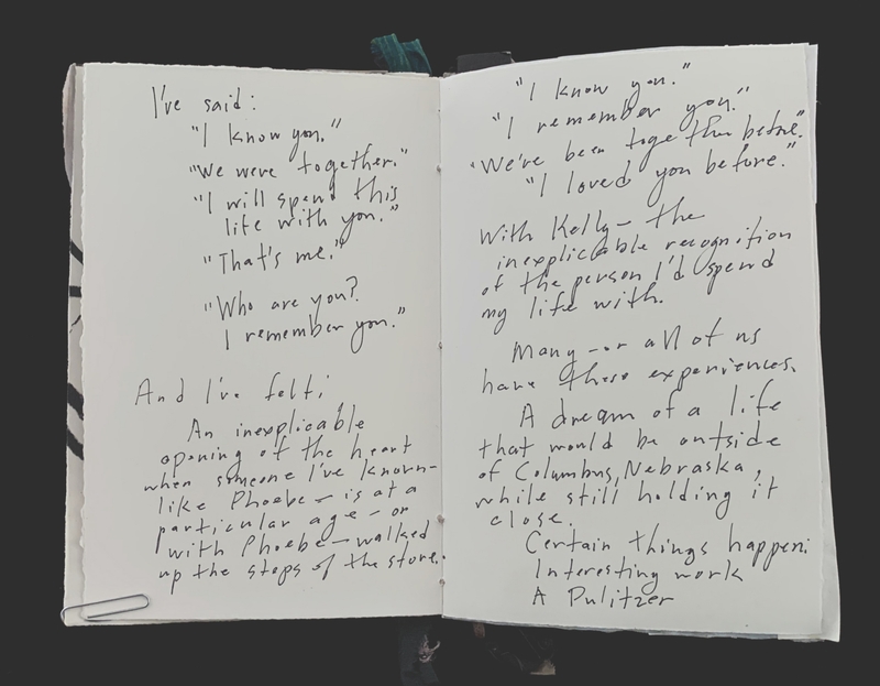 Open notebook with handwritten text on two pages in black ink.