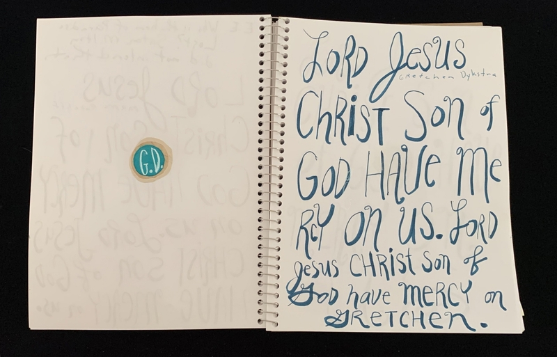 A handwritten page with a prayer and a circular sticker.