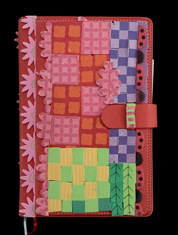 Colorful patchwork design on a red notebook cover with floral and checkered patterns.