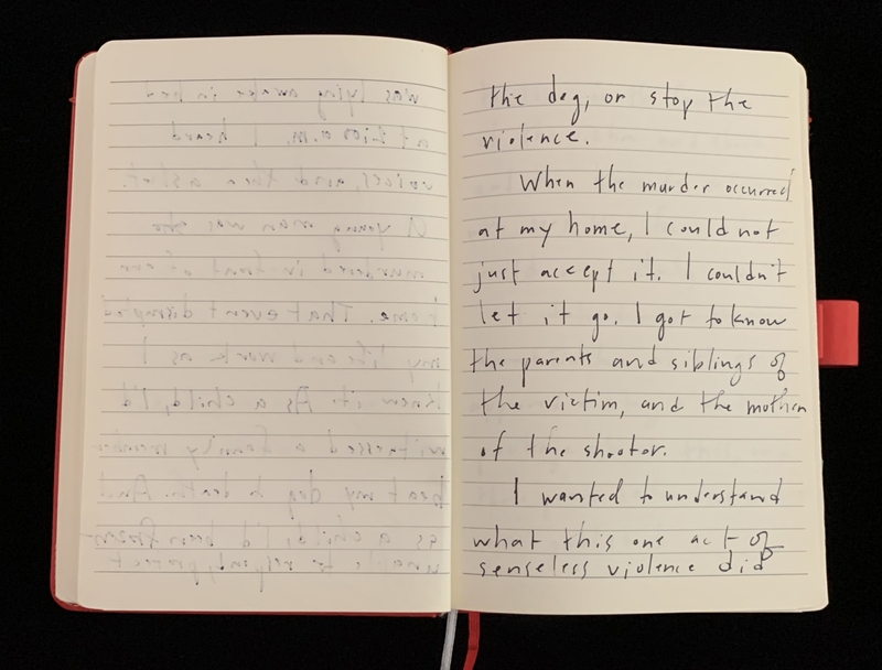 Open notebook with handwritten text on lined pages, one with faint pencil markings and the other with clear pen writing.