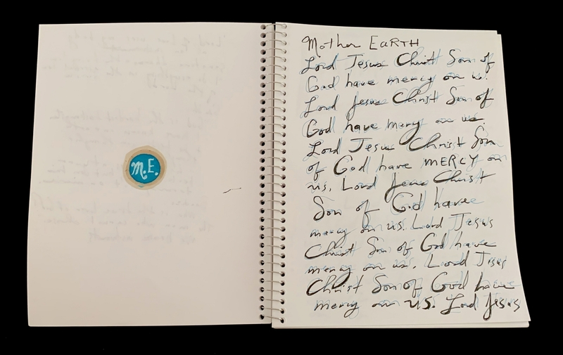 A handwritten page from a notebook with a circular sticker on the left page and repeated prayers on the right page.