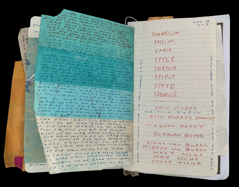 Open notebook with handwritten pages and several colorful sheets tucked into it.