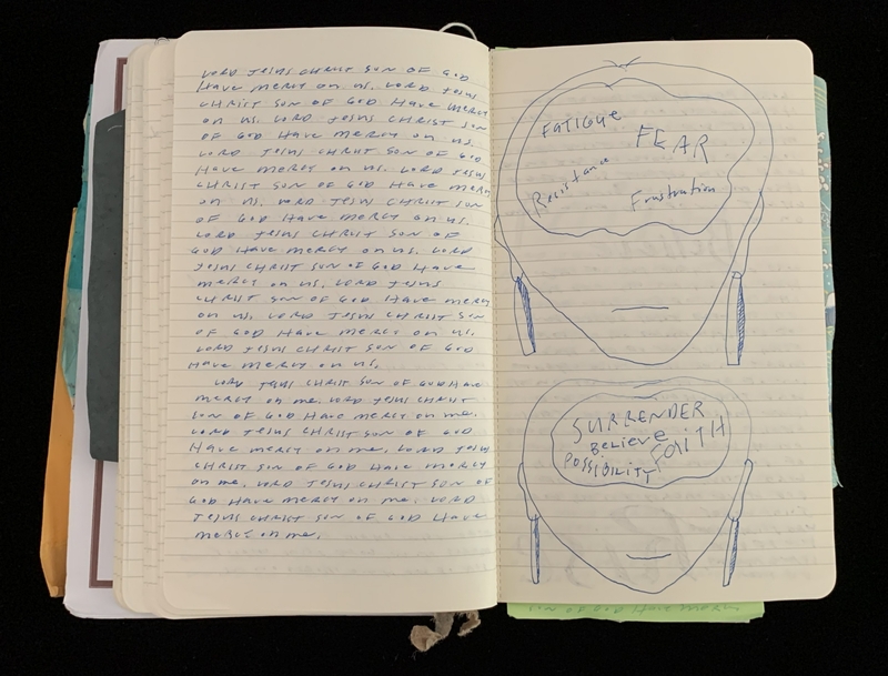 Open notebook with handwritten text on the left page and outlined drawings of faces with words like "Fatigue" and "Surrender" on the right.