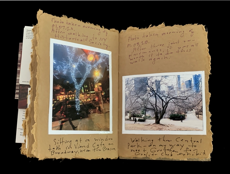 Open scrapbook with two photographs and handwritten notes on brown pages.