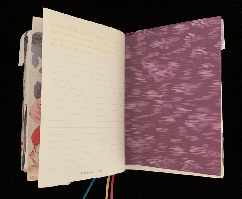An open journal showing handwritten text on a lined page and an abstract purple patterned page.