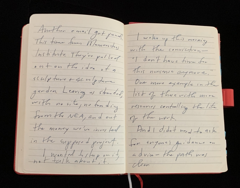 Open notebook with handwritten cursive text on lined pages, bound with a red spine.