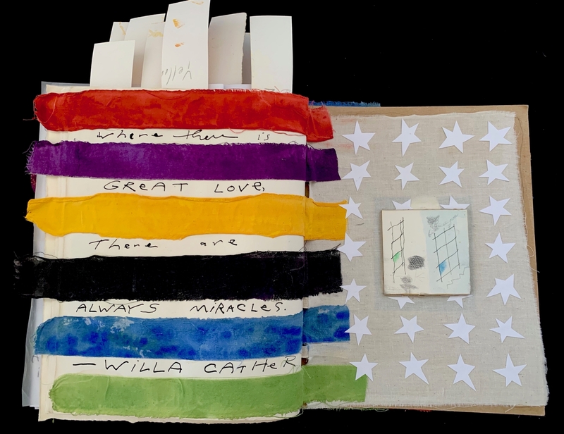 An open journal with colorful fabric strips and handwritten text on one page, and star-shaped cutouts on the other.