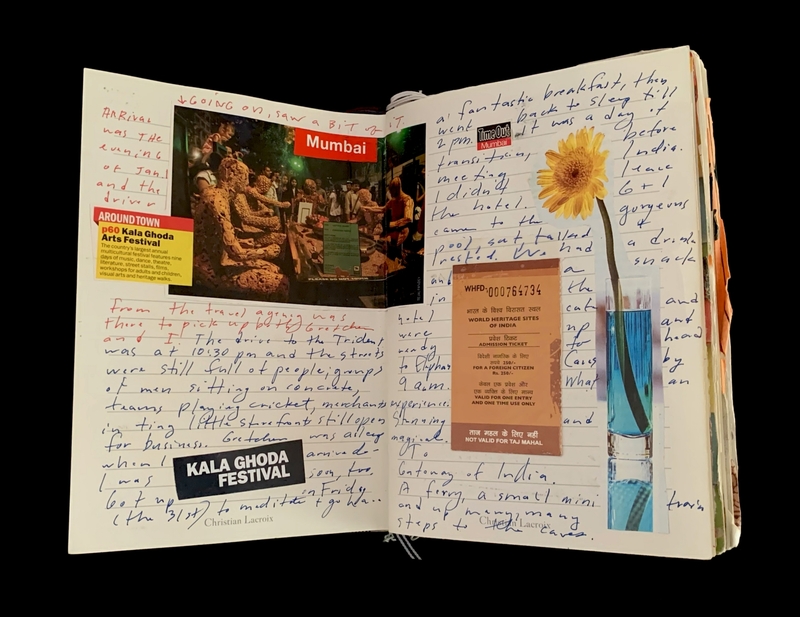 Open journal with handwritten notes, a photo of clay sculptures labeled "Mumbai," a yellow flower in a vase, and a ticket.